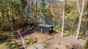 A cabin in a forested area with a dirt path leading to it.