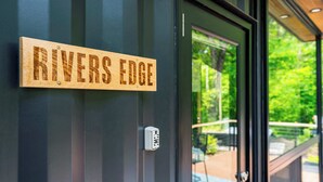 A wooden sign reading "RIVERS EDGE" mounted on a building.