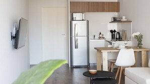 Um espaço de estar moderno e compacto, com cozinha compacta, área de refeições e zona de estar.