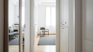 Ein modernes, helles Zimmer mit einem grauen Sofa, einem kleinen Tisch und einem Stuhl.