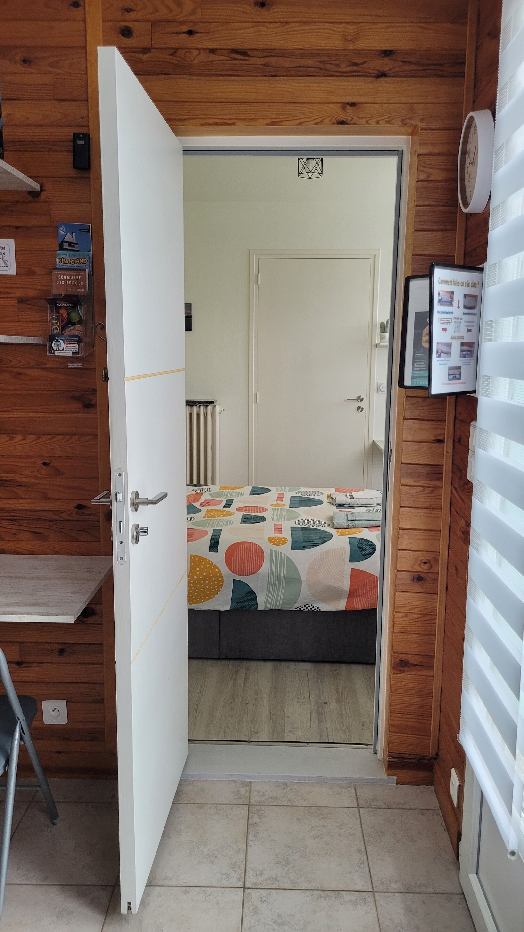 A room with a bed, a door, a radiator, and a poster on the wall.