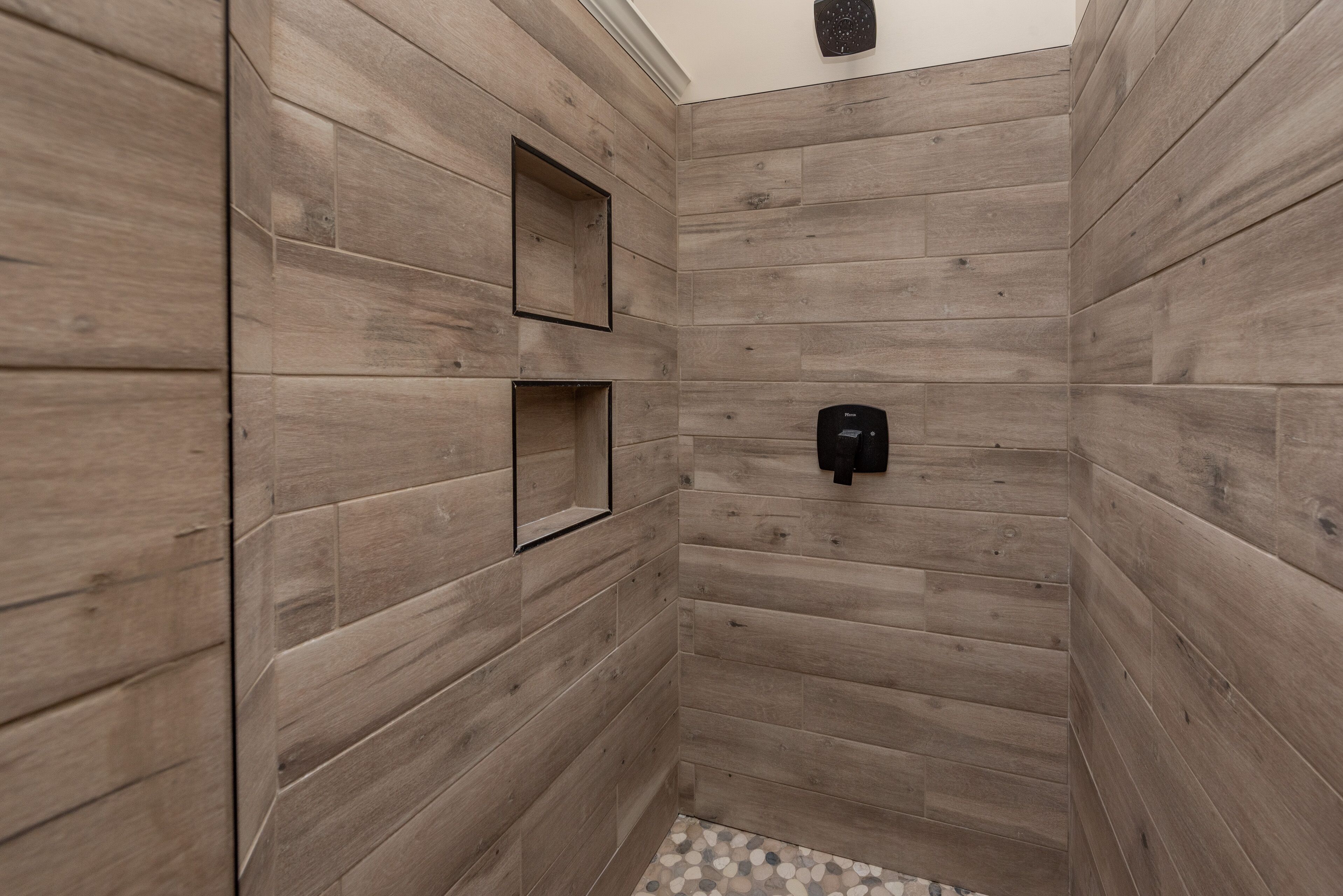 Una ducha con paneles de madera y piso de baldosas.