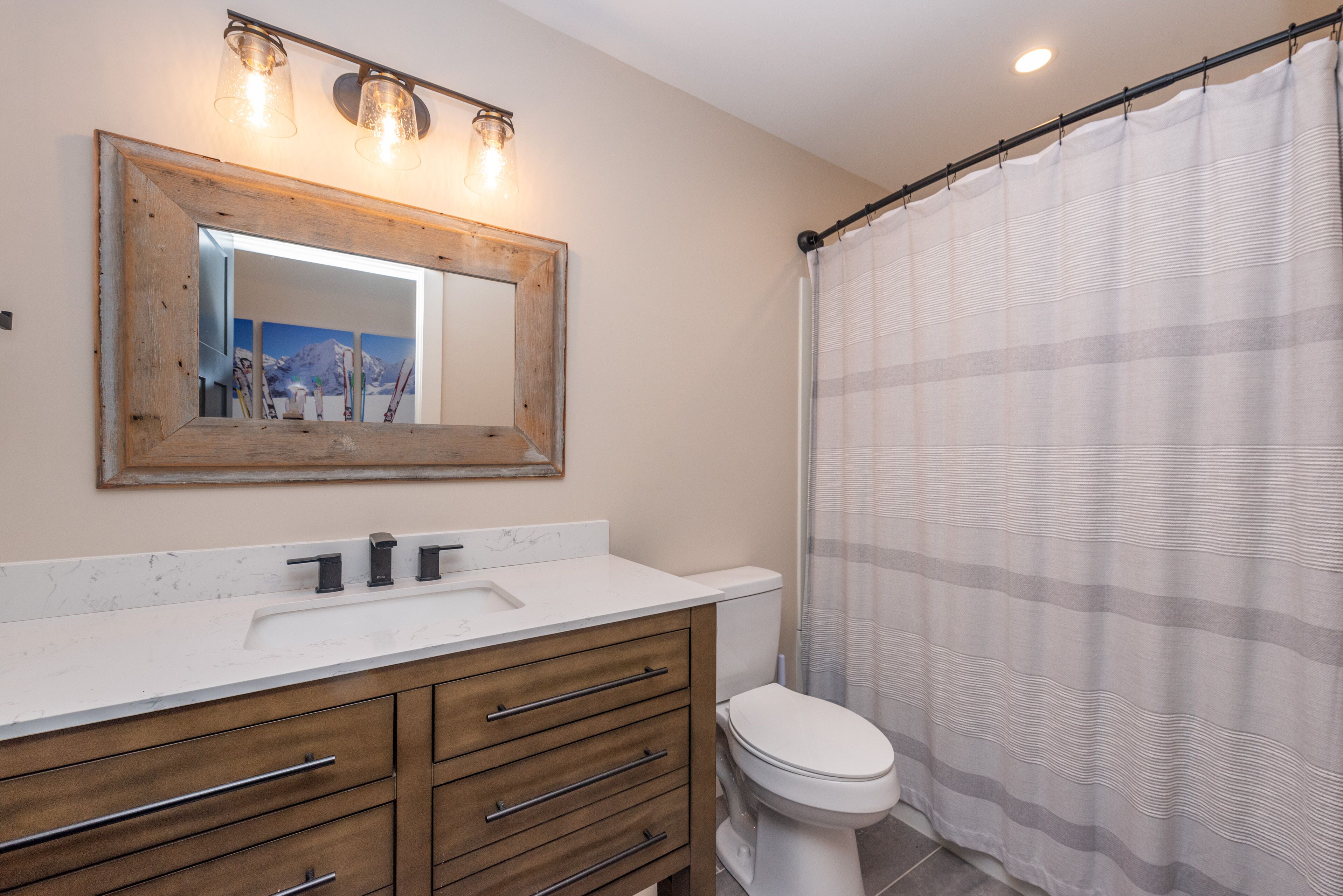A bathroom with a wooden vanity, a white toilet, and a shower curtain.