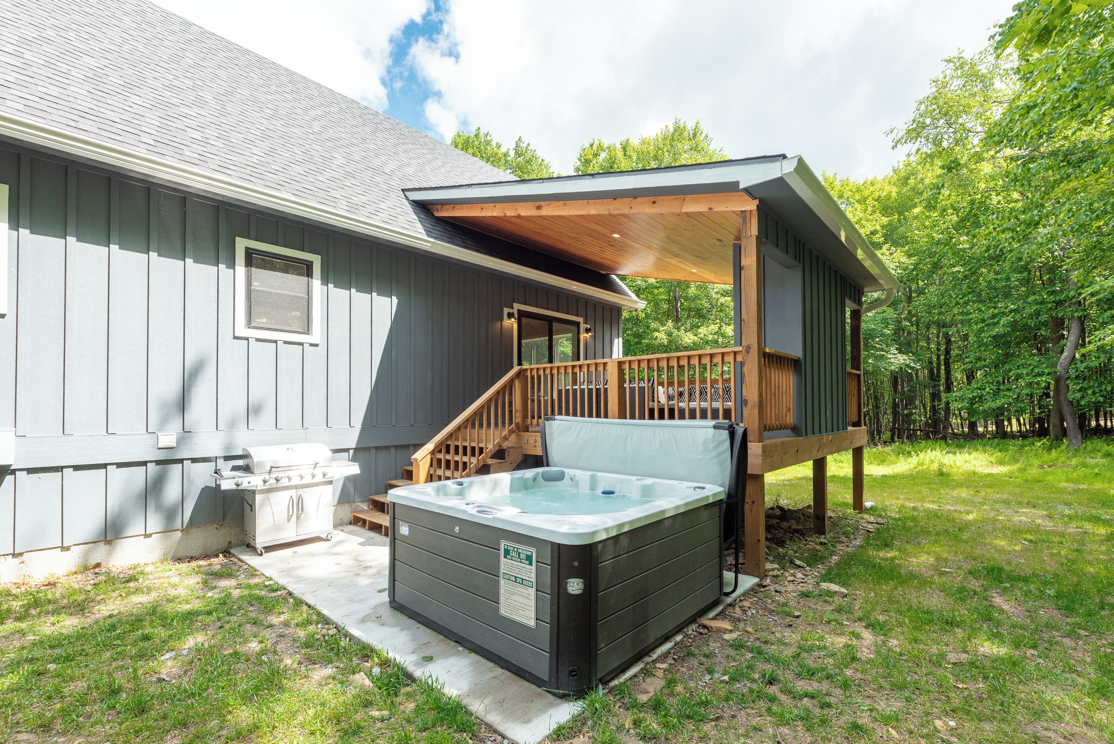 Una casa moderna con jacuzzi, una terraza techada y una escalera que lleva a un segundo nivel.