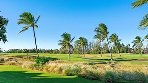 A golf course with palm trees and a clear blue sky.