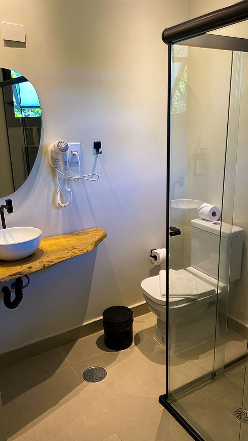A bathroom with a glass-enclosed shower, a sink with a mirror, and a toilet.