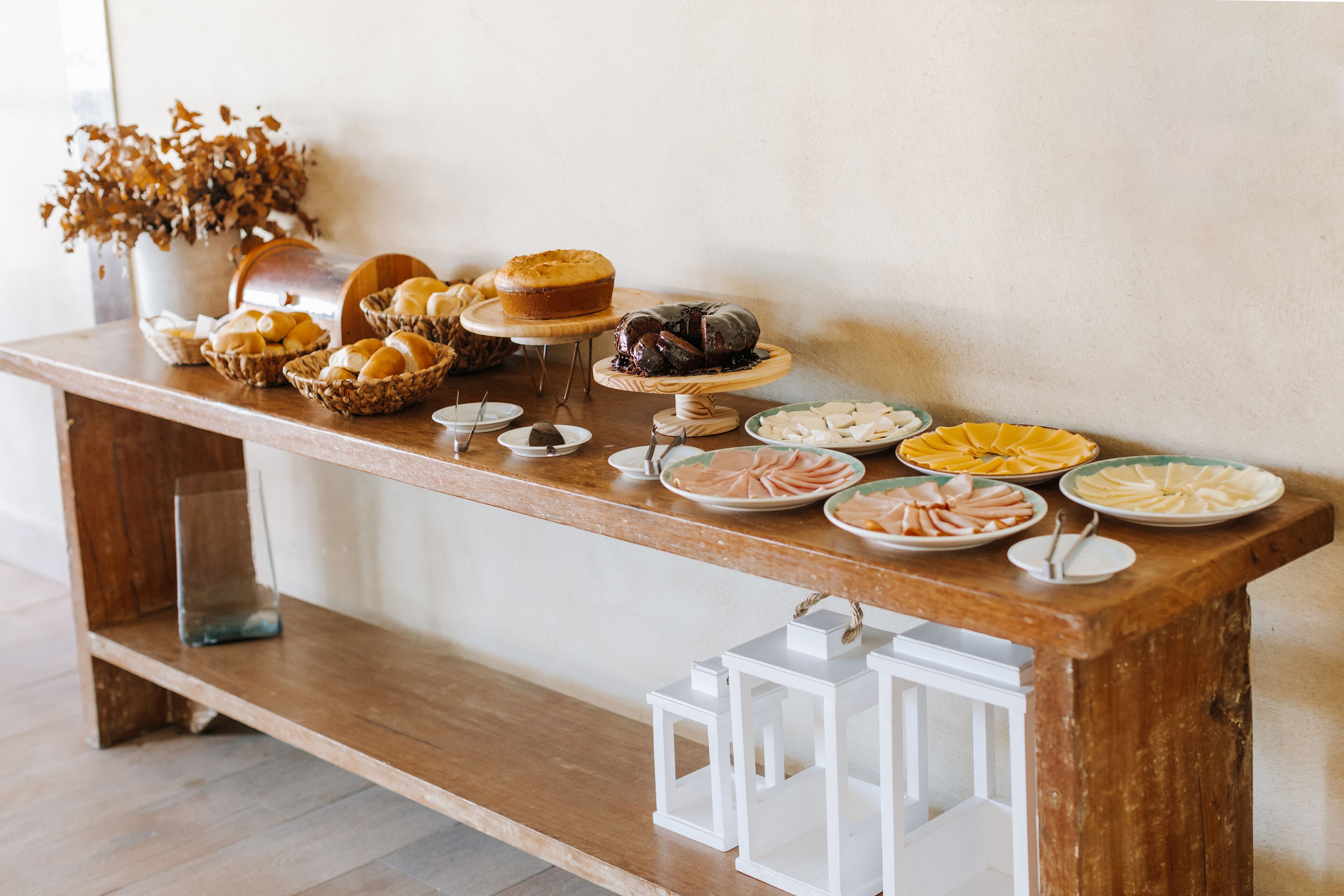 Una mesa de buffet con diversos alimentos y faroles blancos.