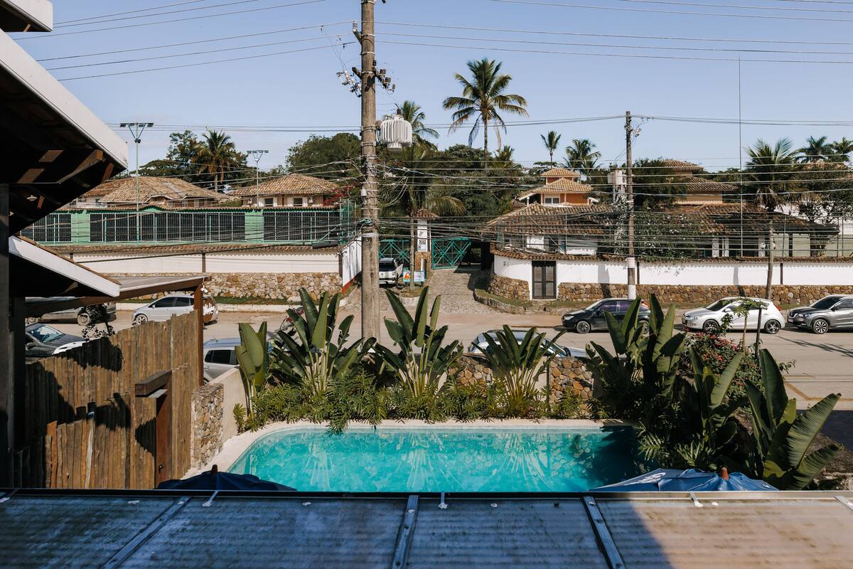 A residential area with a swimming pool, a wooden fence, and a street with parked cars.