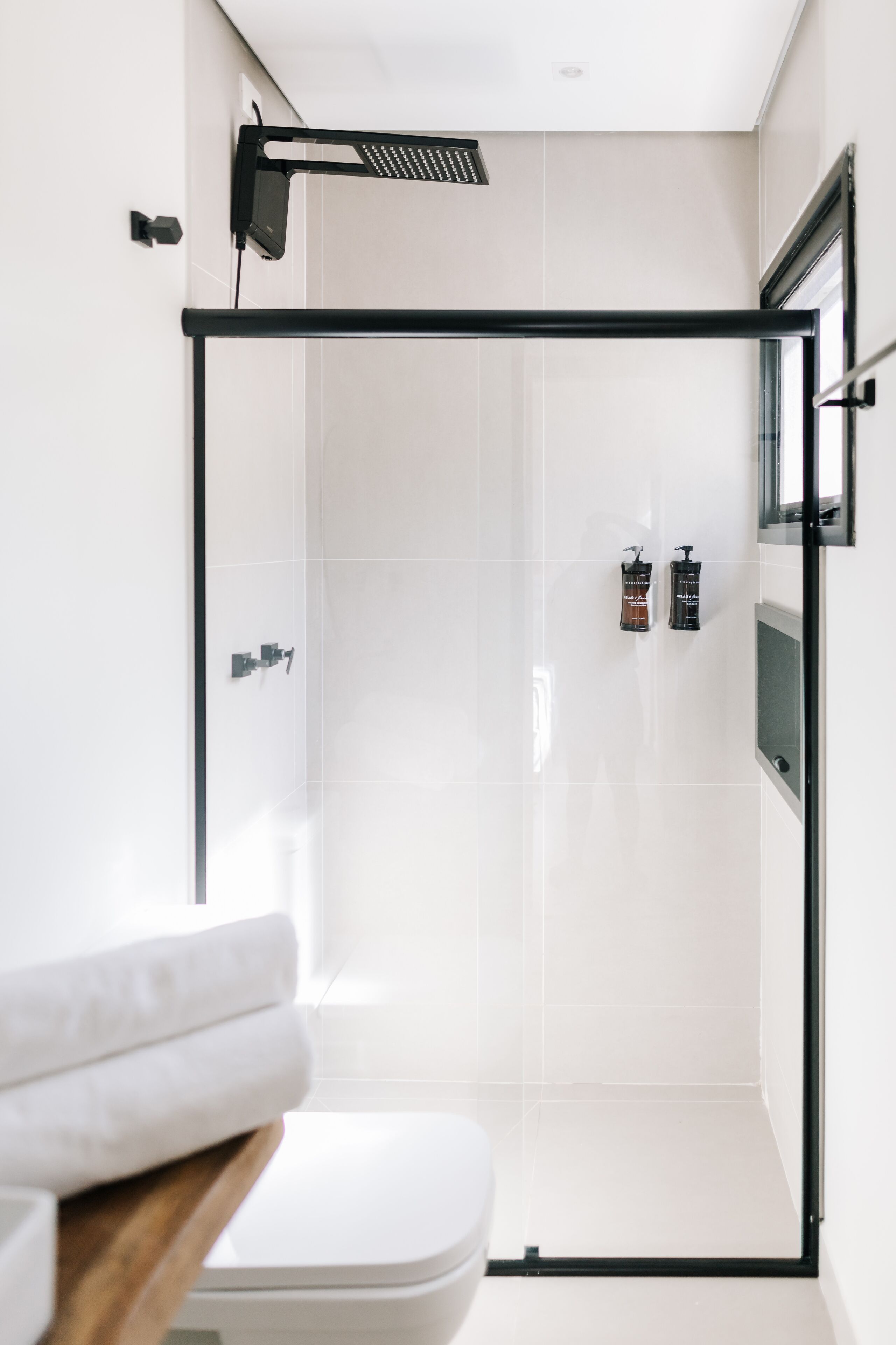 A modern bathroom with a glass shower enclosure, a toilet, and a sink with a wooden countertop.