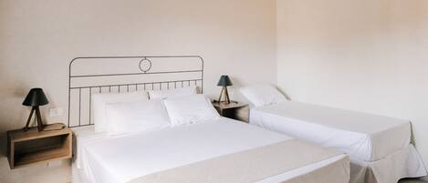 Une chambre avec deux lits, des poutres en bois au plafond, un climatiseur fixé au mur et des tables de chevet avec des lampes.