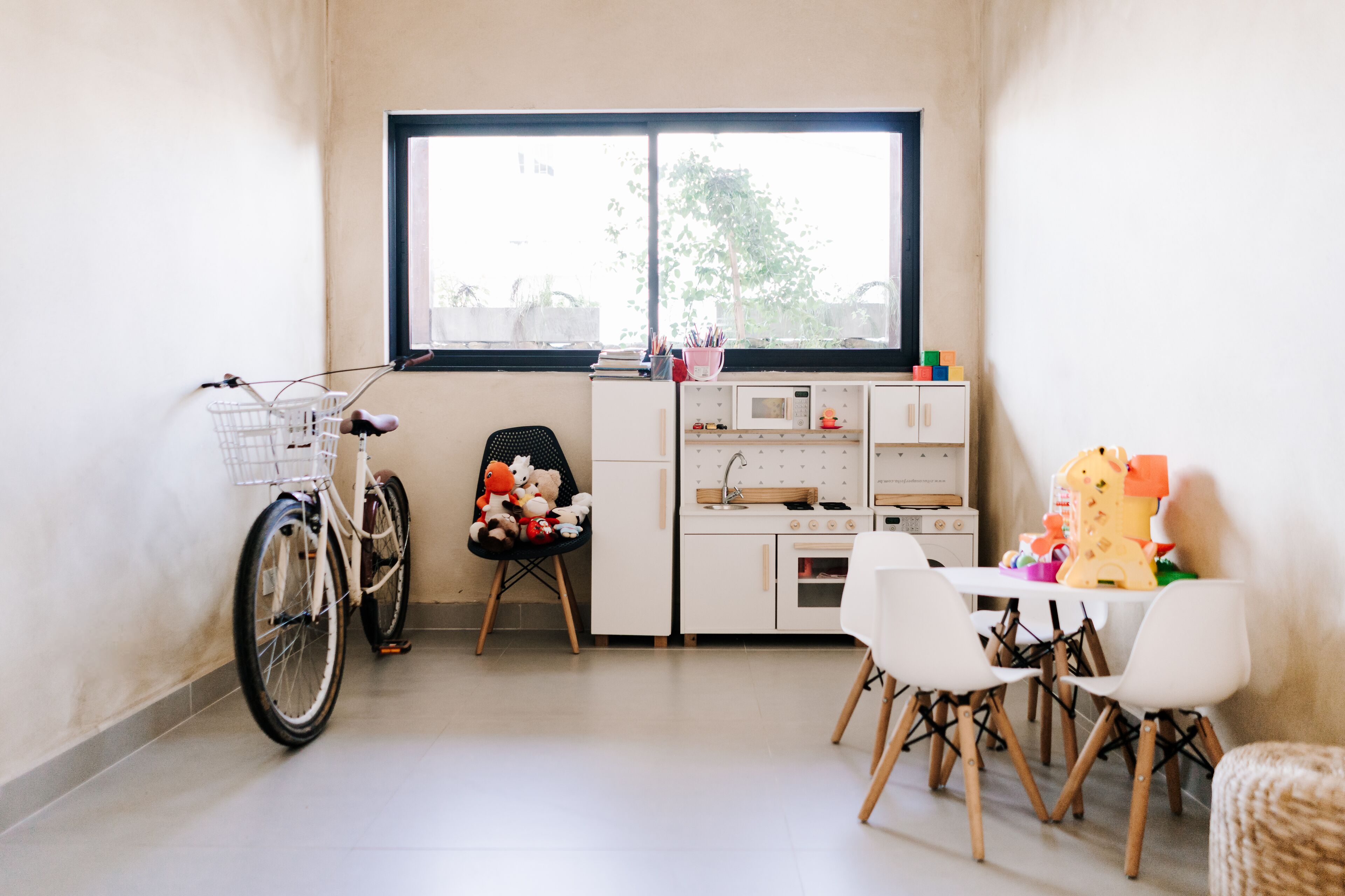 A small kitchen with a dining area, a bicycle, and a window with a view of trees.