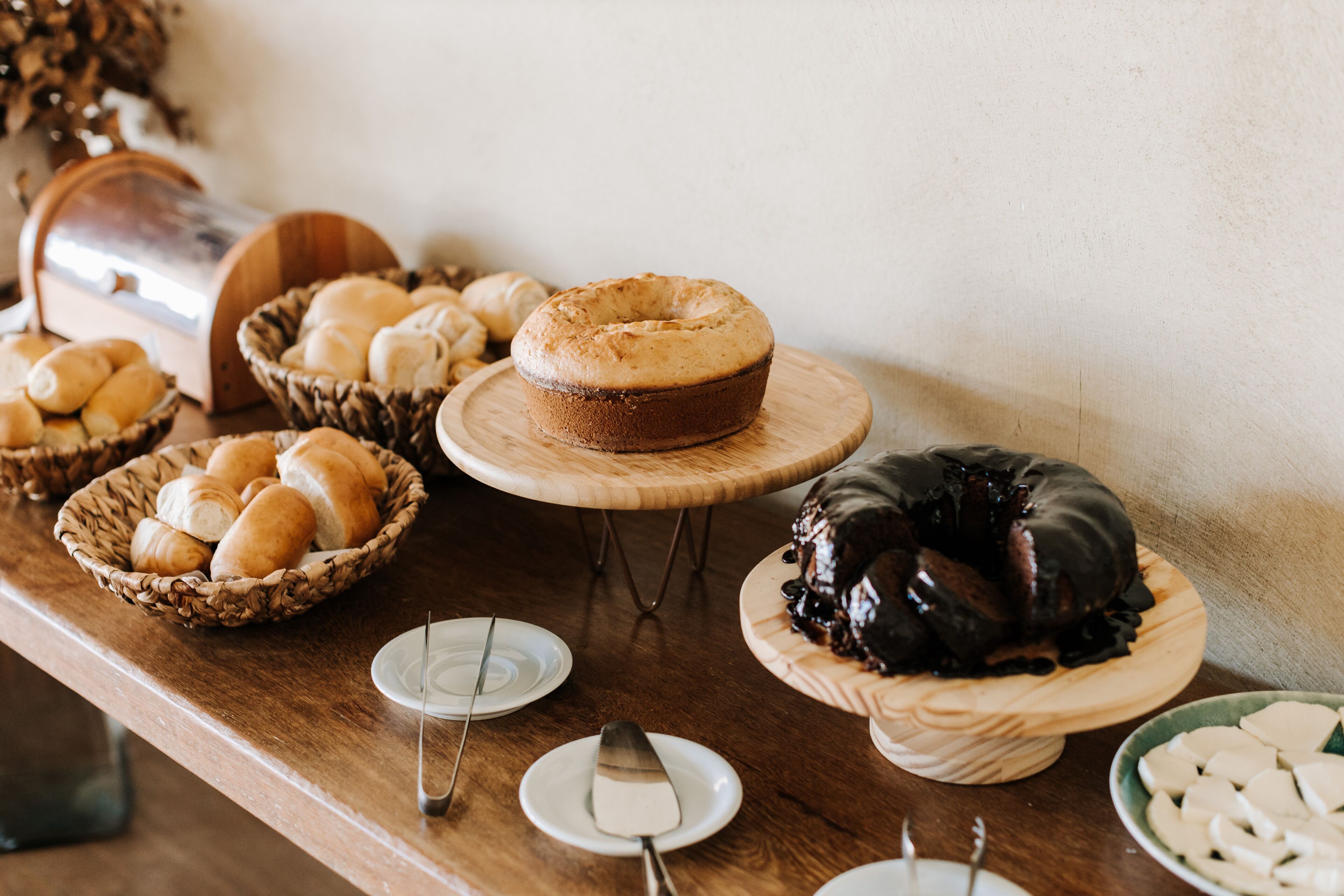 A buffet table with various baked goods, including bread rolls, a cake, and a chocolate dessert.