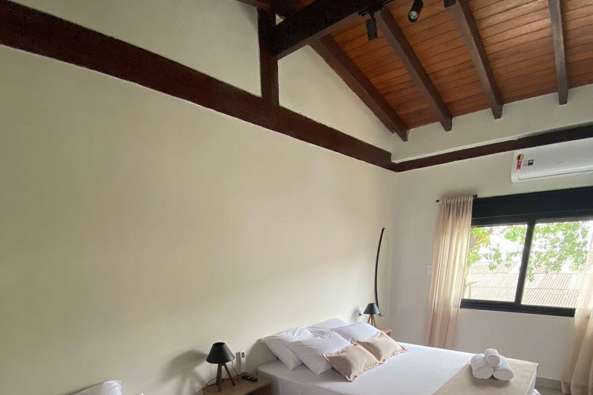 A hotel room with two beds, a nightstand with a lamp, and a window with curtains.