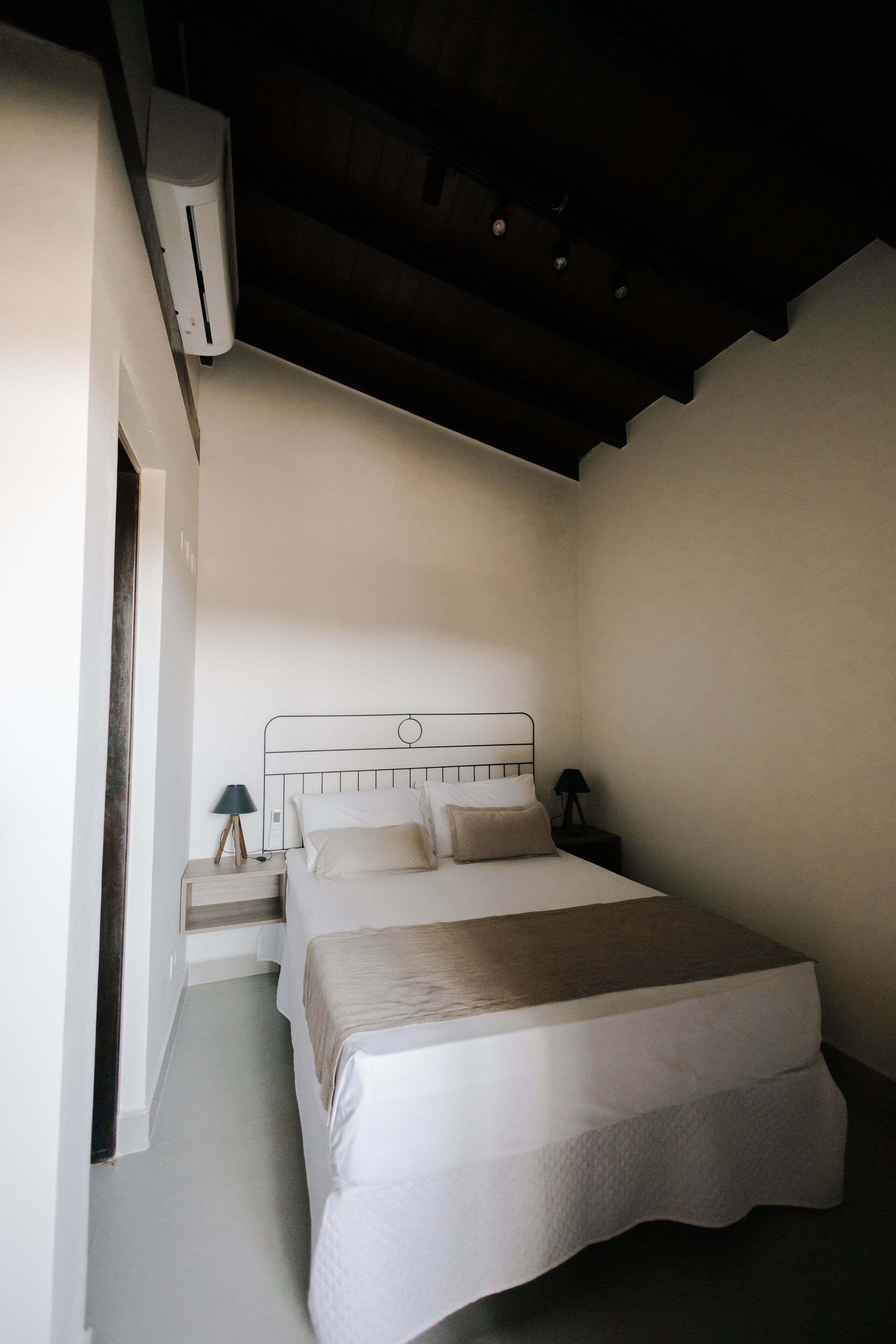 A bedroom with a bed, bedside tables, and an air conditioning unit.
