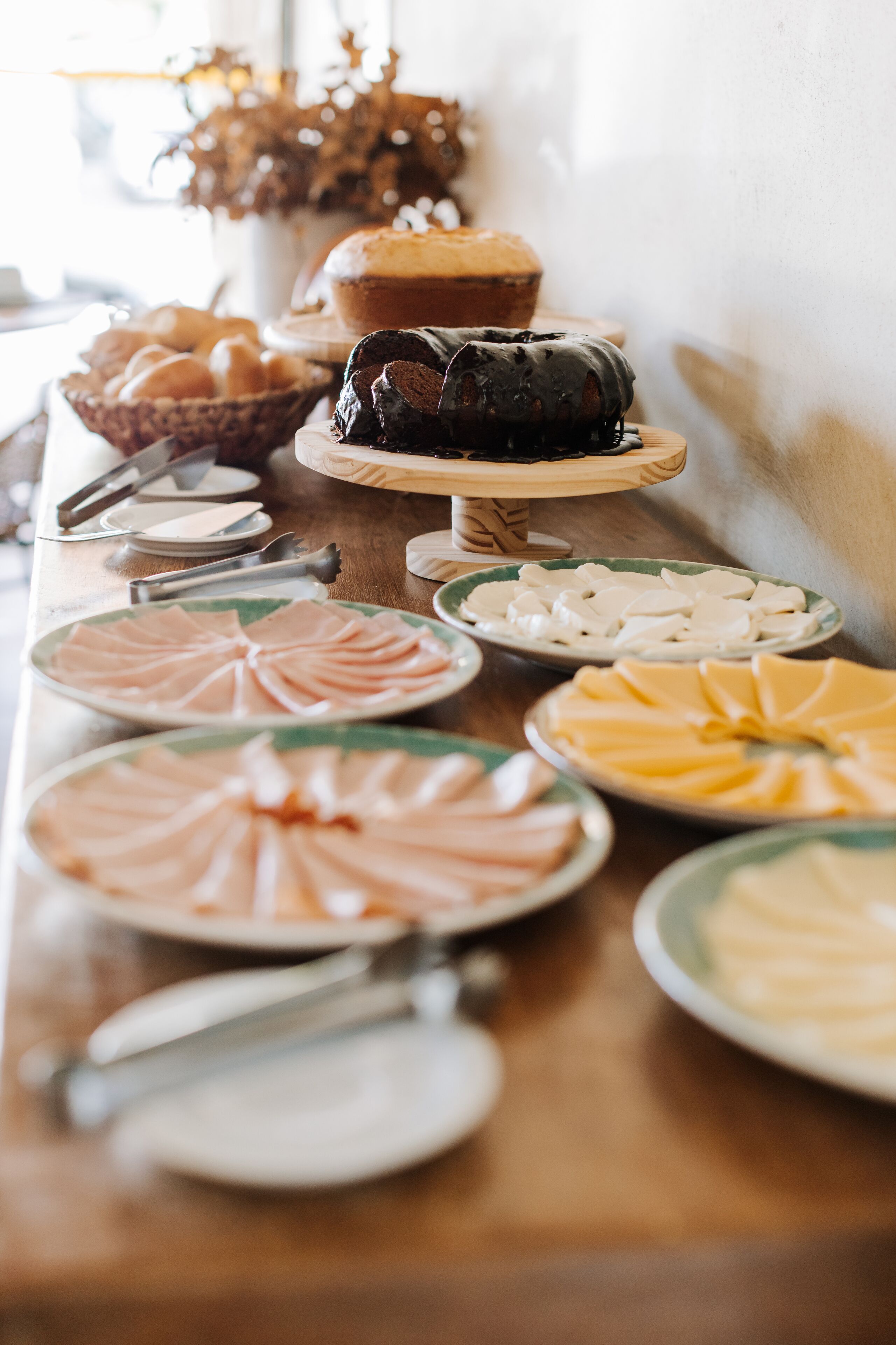 Mesa de buffet com diversos alimentos, incluindo doces, bolos e fatias de carne.