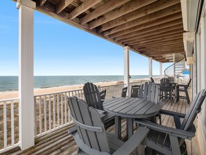 A wooden deck with Adirondack chairs and a table, overlooking a beach. - Beach Buzz: Beachfront, Private Pool, Hot Tub (St. George Island)