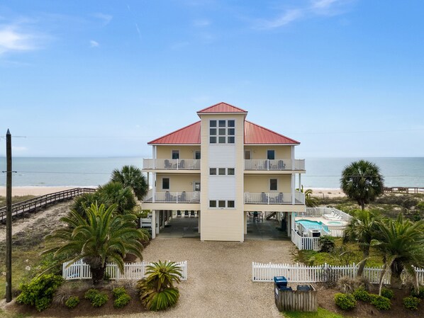 A multi-story beachfront building with balconies, a pool, and a sandy beach area. - Beach Buzz: Beachfront, Private Pool, Hot Tub (St. George Island)