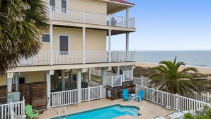 A two-story building with a pool, outdoor seating, and a view of the beach. - Beach Buzz: Beachfront, Private Pool, Hot Tub (St. George Island)