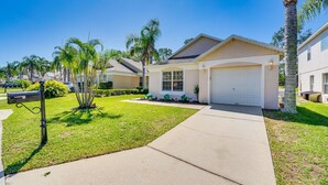 A residential house with a front yard, a driveway, and a garage. - Beautiful 3-bedroom house, with private pool, backing onto golf course (Haines City)