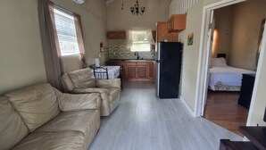 Ett kompakt bostadsutrymme med en soffa, ett litet kök och en tv.