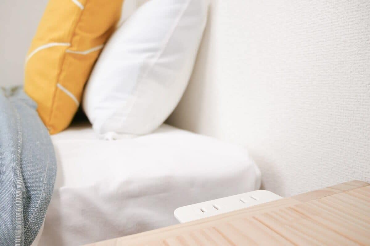 Parte de una habitación con un sofá blanco, una mesita de madera y un enchufe.