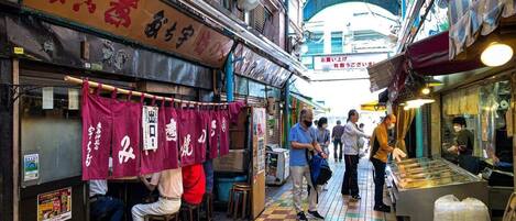 A narrow alley with shops on both sides, a tiled floor, and a covered walkway overhead.
