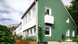 A green house with white windows and a small balcony. - Greenhouse Apartments (Helgoland)