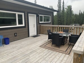 A deck with a table and chairs, a door, and a blue trash bin.