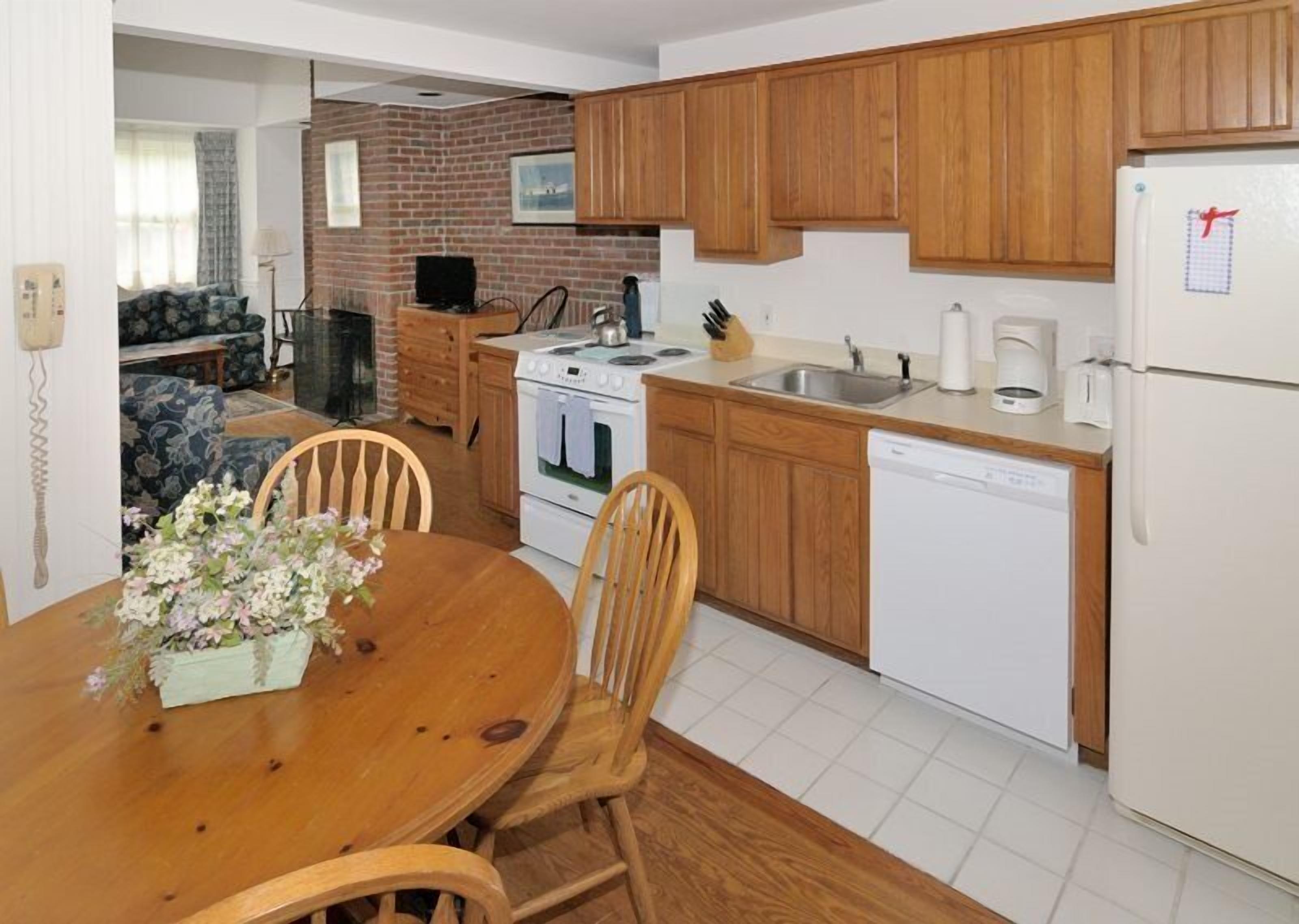 A compact kitchen with wooden cabinets, a stove, a sink, and a dishwasher.