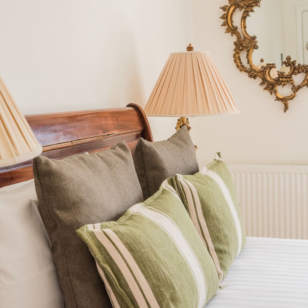 A bed with striped pillows, a wooden headboard, and two lamps on either side.