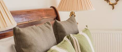 Una cama con almohadones a rayas, un cabecero de madera y dos lámparas a cada lado.