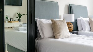 A hotel room with a bed, a nightstand with a lamp, and a TV mounted on the wall. - The Retreat New Forest (Christchurch)