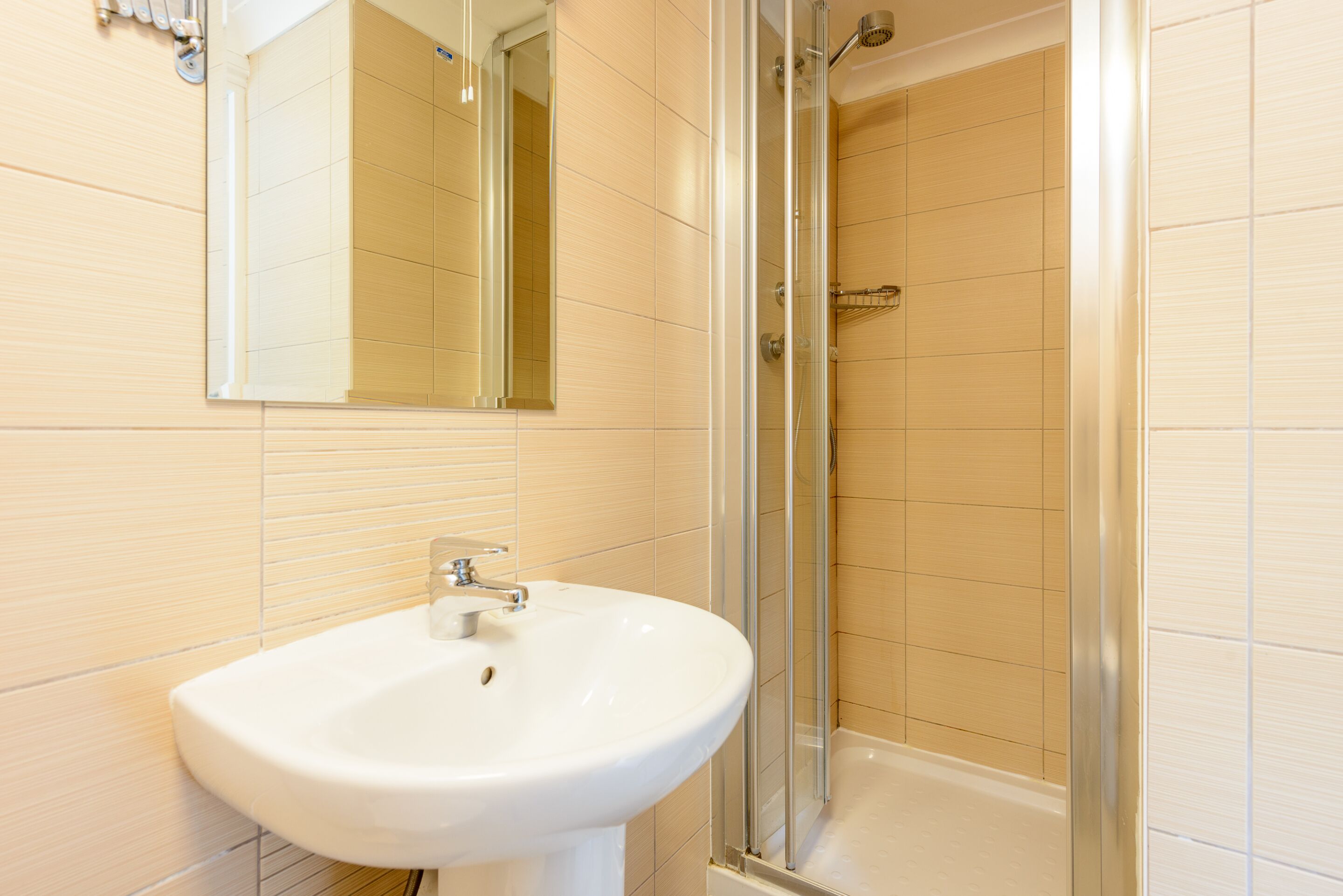 A bathroom with a white sink, a mirror, and a glass-enclosed shower.