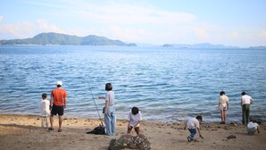Un groupe de personnes se trouve près d’une étendue d’eau calme, avec des montagnes qui se dessinent à l’horizon.
