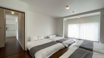 A modern bedroom with two beds, a walk-in closet, and a large window with blinds.