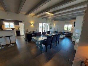 Amplia sala de estar con mesa de comedor, sofás y zona de cocina con un ventanal grande.