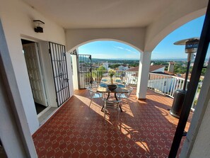 A balcony with a tiled floor, a table with chairs, and a view of the cityscape. - Modern villa with stunning views and swimming pool. (L'Escala)