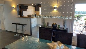 Une cuisine moderne dotée d’un îlot central, de luminaires suspendus et offrant une vue sur l’extérieur.