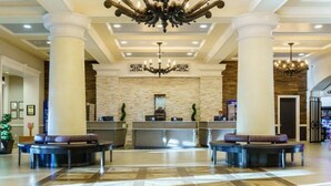 A hotel lobby with a reception desk, two seating areas, and a chandelier. - Spend Christmas in this luxurious condo in Vegas! (Las Vegas)