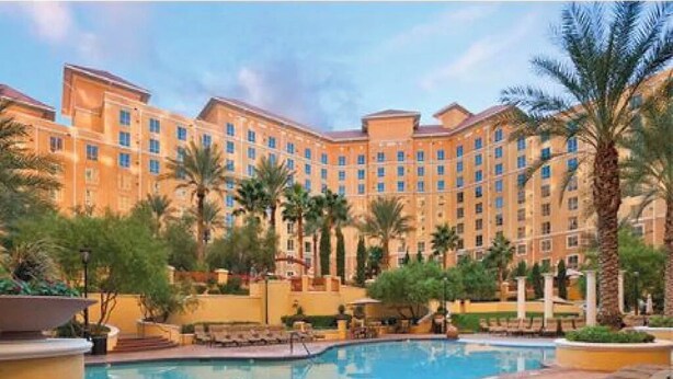 A hotel with a swimming pool surrounded by palm trees and lounge chairs. - Spend Christmas in this luxurious condo in Vegas! (Las Vegas)