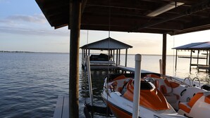 A boat docked at a pier with a covered area overhead. - Relaxing Renovated Cottage on  Lake June in Winter with Dock! (Lake Placid)