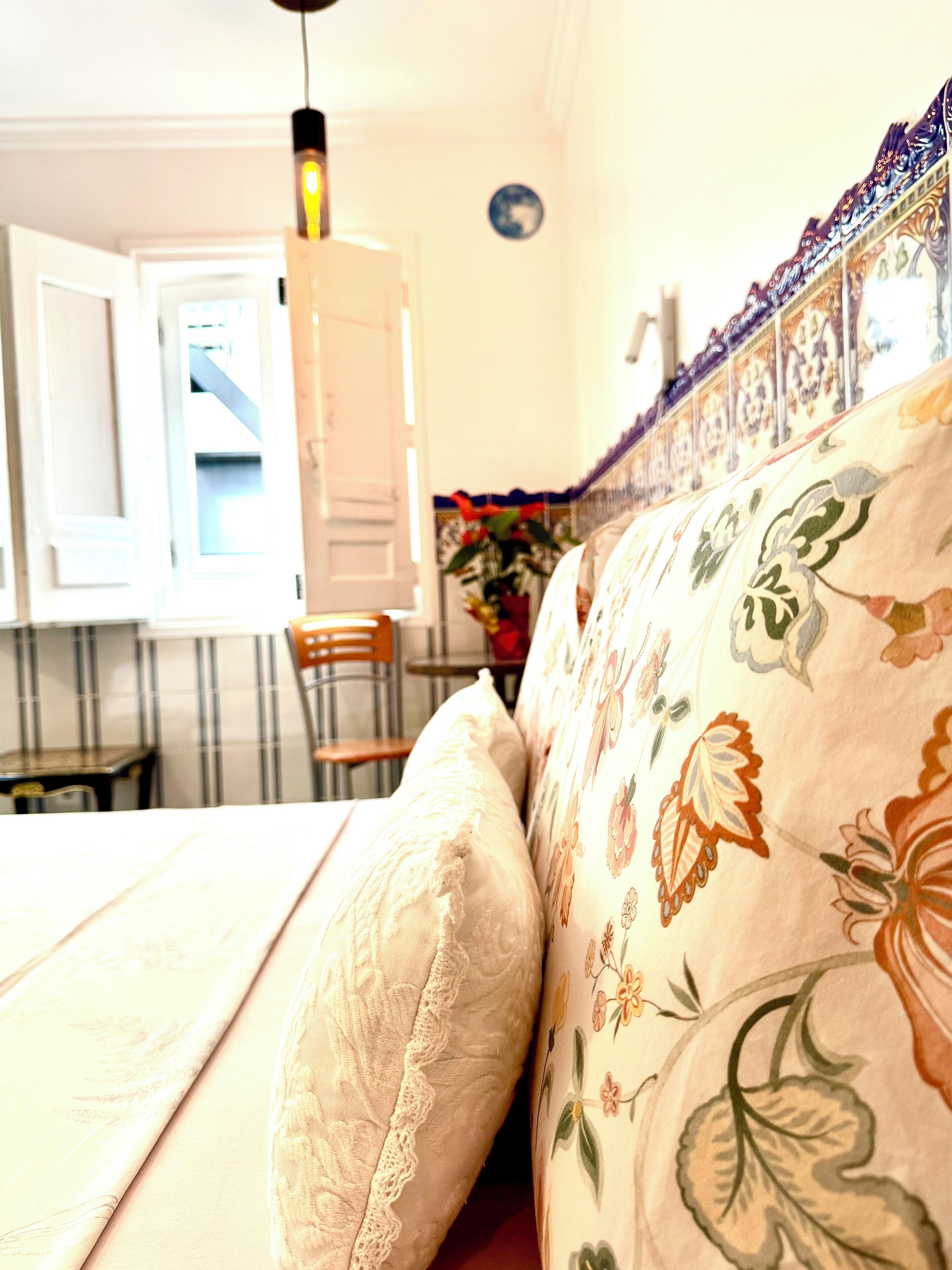 A bed with floral-patterned bedding, a wooden headboard, and a white door in the background.