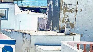 A rooftop with a view of the sea, featuring a building with a bell tower and a balcony.