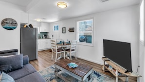 Een moderne woonkamer met een grijze bank, een houten salontafel en een tv op een dressoir.