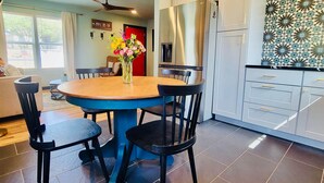 A modern kitchen with a dining area, featuring a round table, chairs, a refrigerator, and a patterned backsplash.