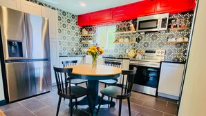 A modern kitchen with a dining area, stainless steel appliances, and patterned backsplash.