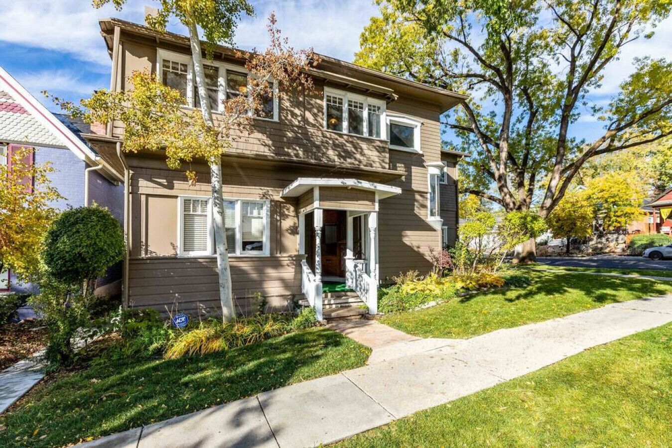 A two-story house with a front porch, a small front yard, and a driveway.