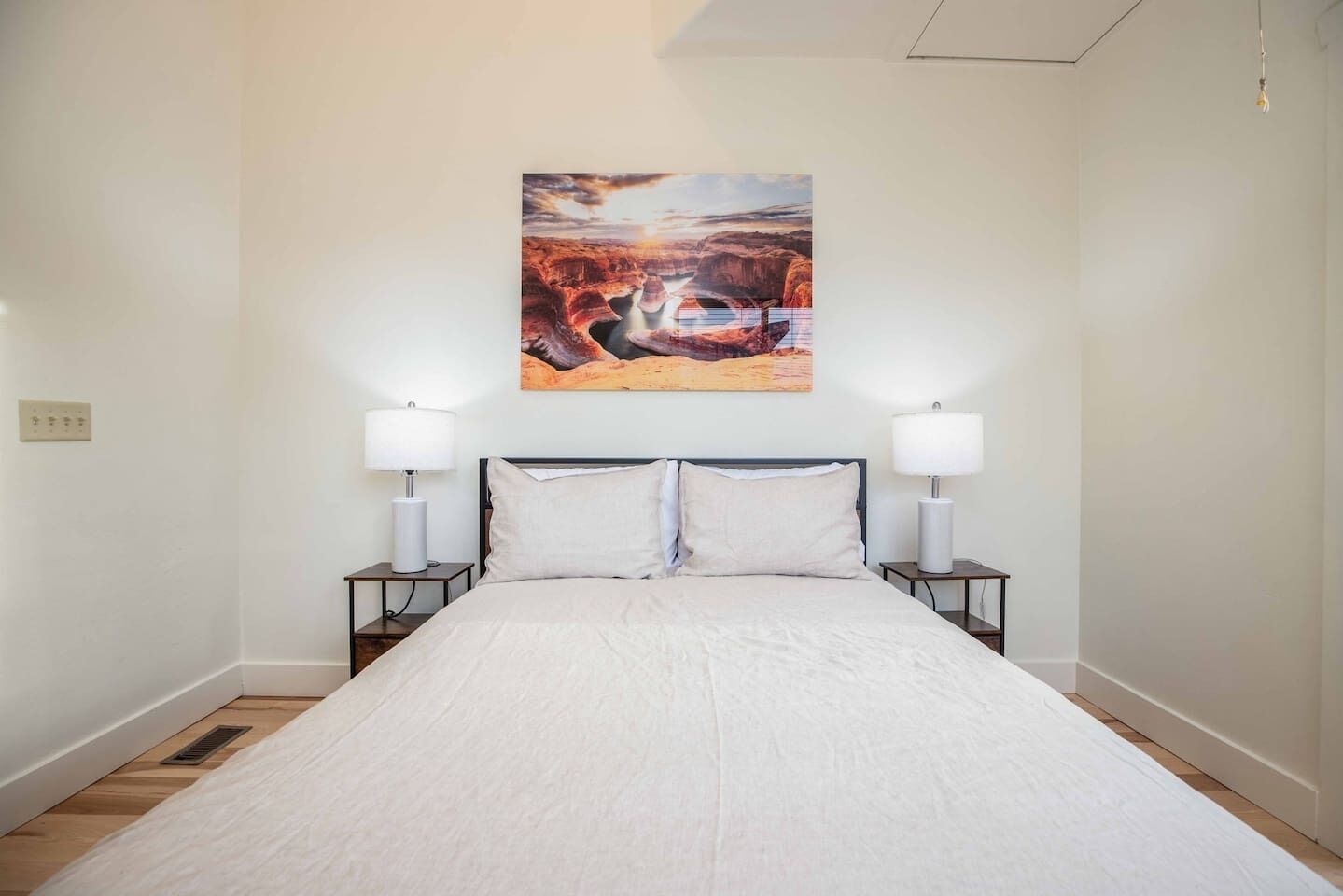 Un dormitorio con una cama grande, dos mesitas de noche con lámparas y un cuadro en la pared.