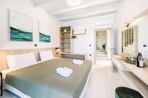 A hotel room with a bed, a bedside table, a mirror, and artwork on the wall.