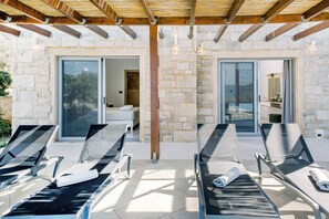 Un espace extérieur abrité, aménagé avec des fauteuils confortables et un mur en pierre.